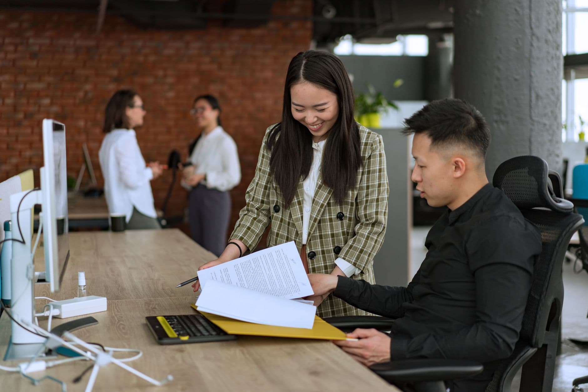 Two colleagues reviewing paperwork together at a desk